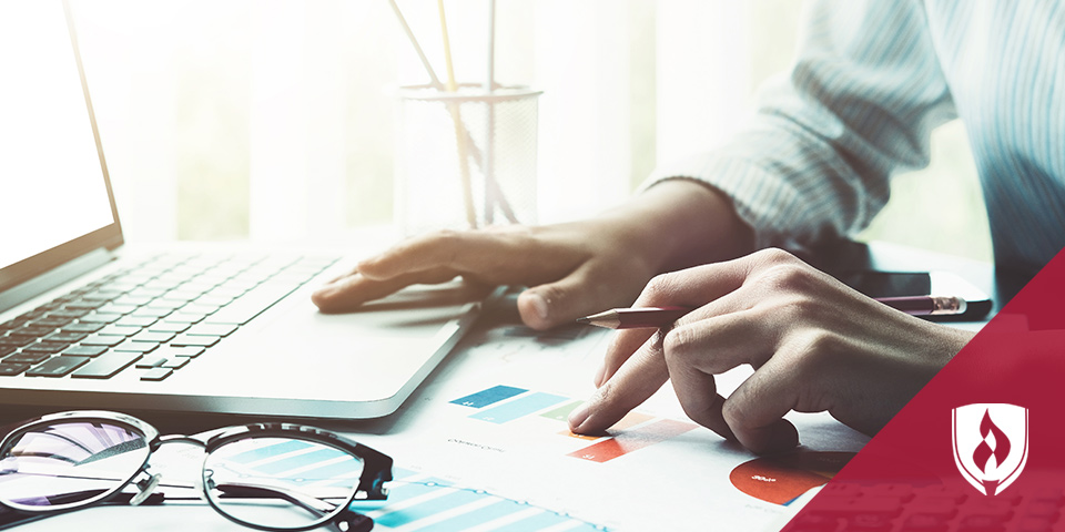 会计在笔记本电脑上工作，核对打印图表上的数字