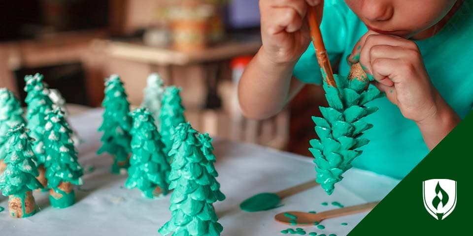 illustration of toddler painting wooden christmas trees representing winter activities for preschoolers