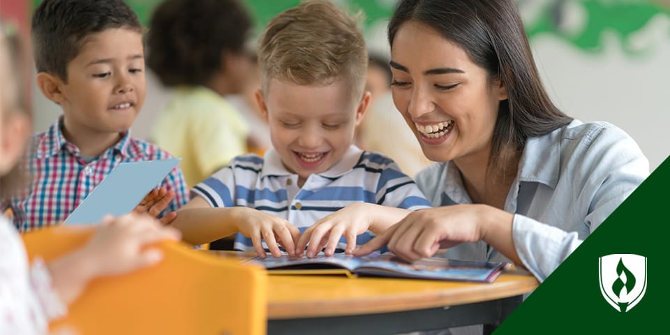 smiling female teacher helping children at a table