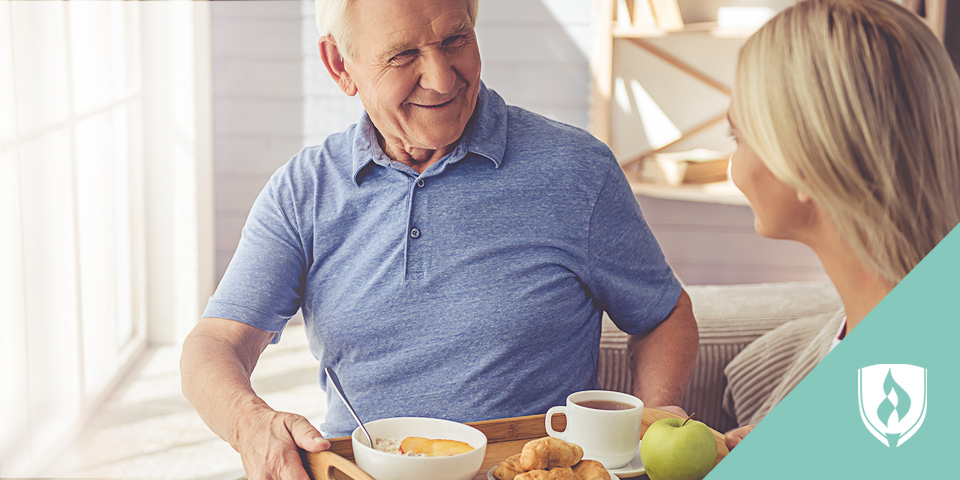elderly man receiving his breakfast from a young lady