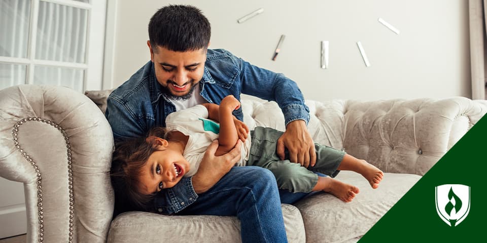 照片显示一个孩子和成年人玩 代表粗糙和滚动游戏