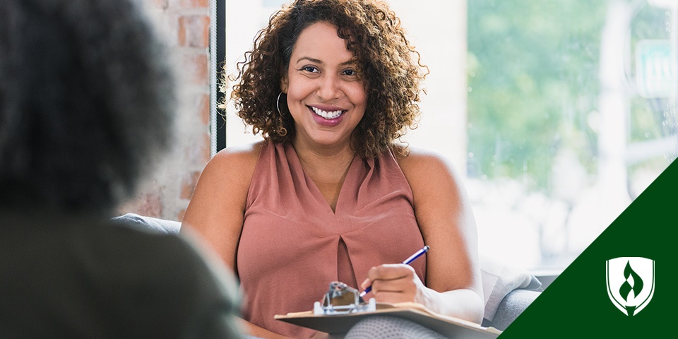 photo of a human services professional smiling at a client and writing on a clipboard